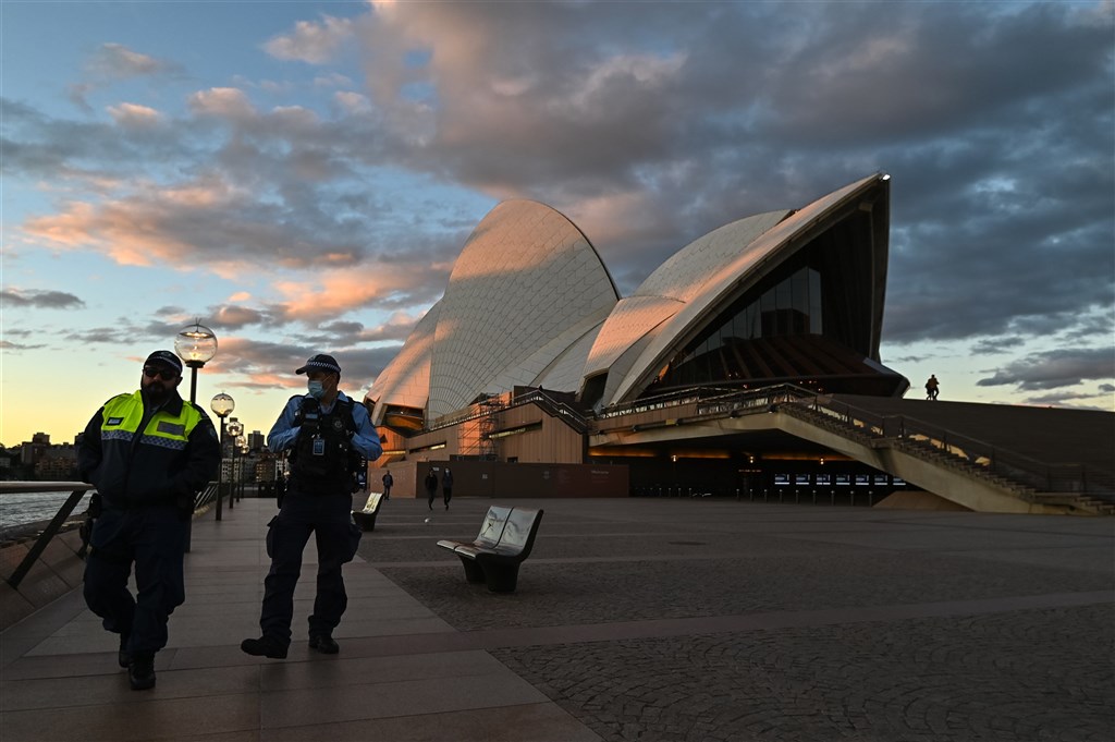 Delta變異株擴散，澳洲雪梨、達爾文、伯斯、布里斯本相繼採取防疫居家令，如今有約1000萬人受到封城影響。圖為26日警察在雪梨歌劇院外巡邏。（安納杜<a href=
