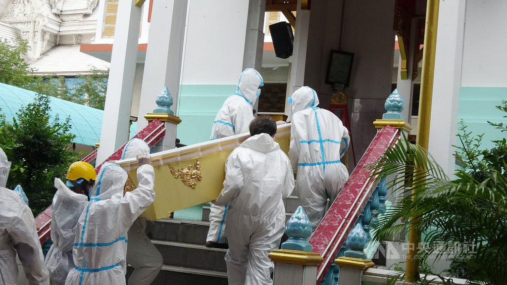 泰國第三波疫情嚴峻，8月中旬以來死亡人數每日新增破200人，寺廟協助火化死者屍體，圖為工作人員和僧侶穿上防護衣搬運棺材到火化爐前。中央社記者呂欣憓曼谷攝.jpg
