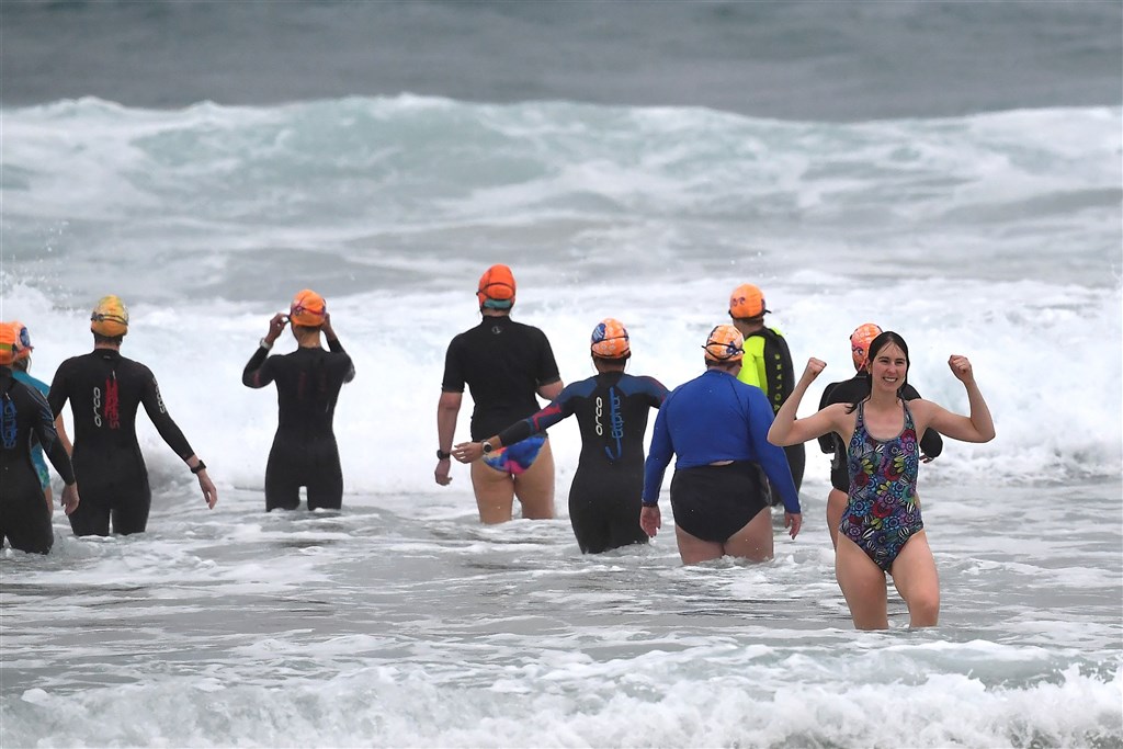 澳洲最大城雪梨實施近4個月的防疫封鎖措施後，11日迎來解封，民眾不甩灰濛天空和雨勢，開心到海邊戲水。（法新社）.jpg