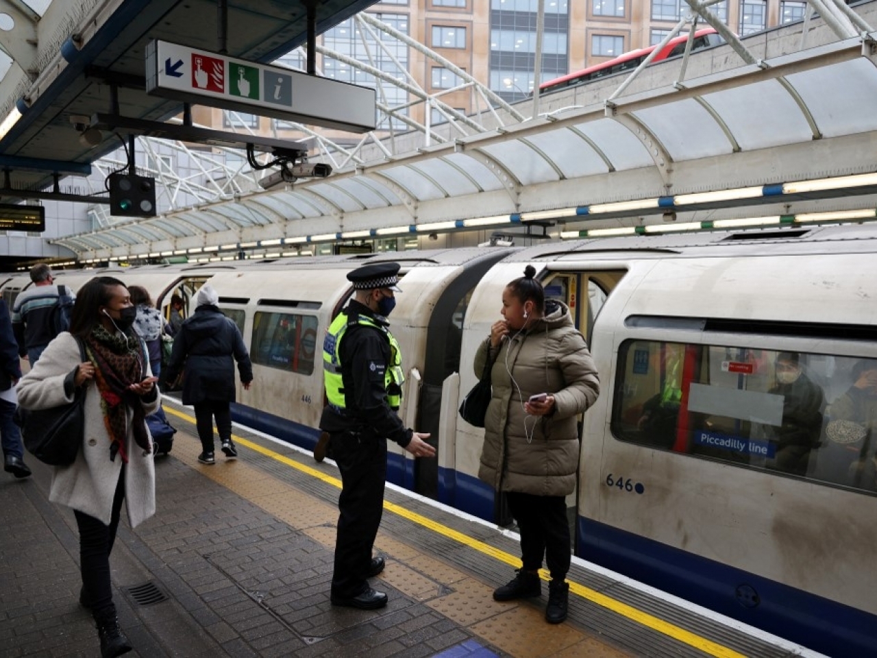 英國相信Omicron變種新冠病毒正在社區擴散，有警員截查無戴口罩的乘客。（法新社）.jpg